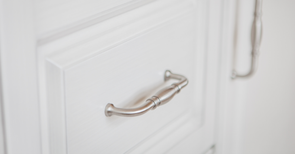Traditional decorative handle in brushed nickel on traditional white raised panel cabinets.