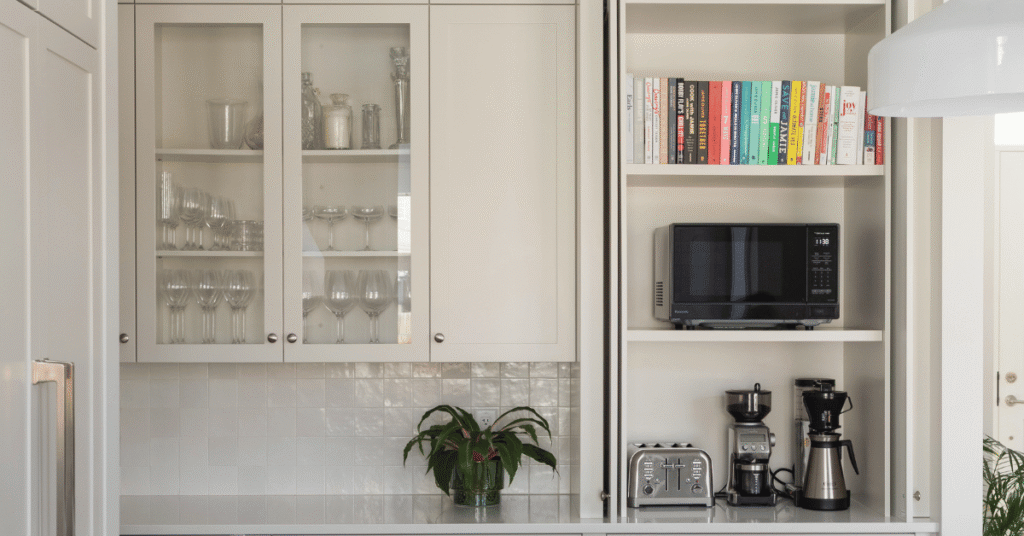 A white kitchen with a wall counter tall appliance garage cabinet with flipper doors, the doors are open, showcasing what's inside.